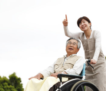 caregiver and elder man on wheelchair looking at distance